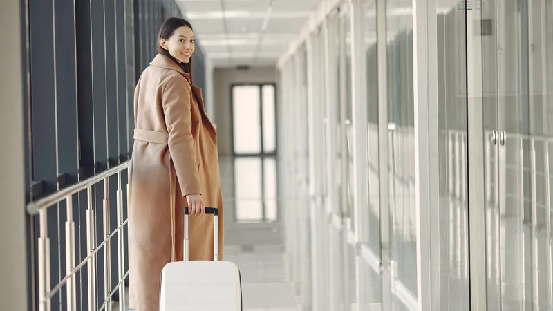 A traveller walking through an airport terminal with her suitcase.