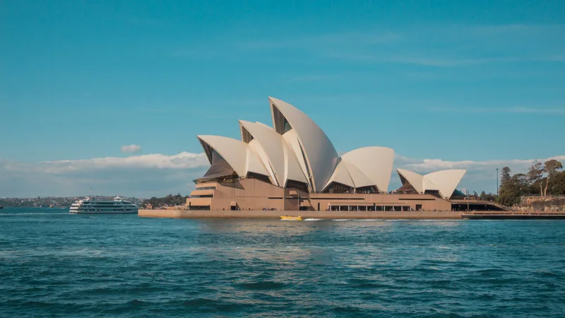 The white sails of Sydney Opera House beside blue harbour water.